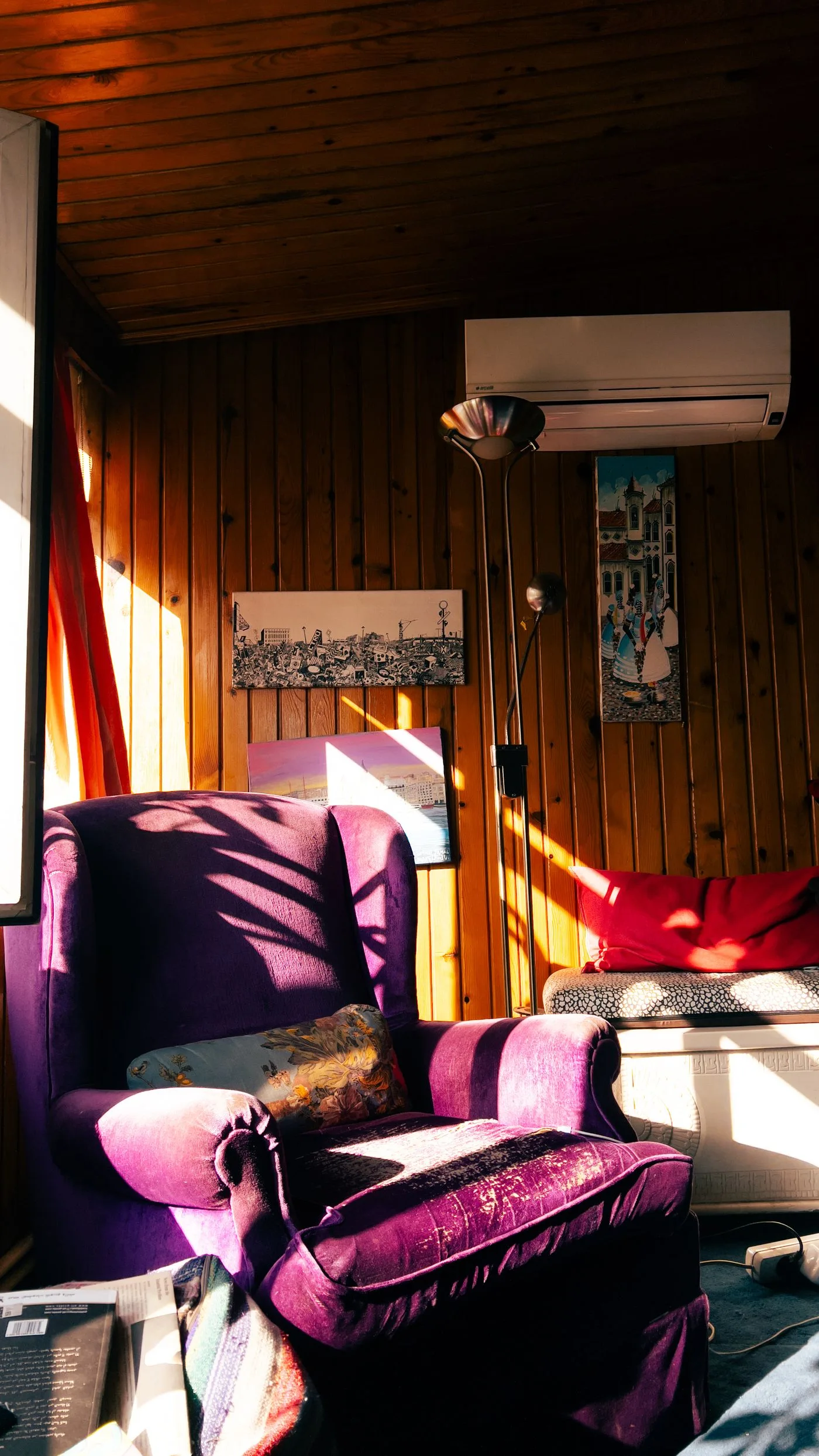 A sunlit room in Istanbul features a vibrant purple chair, wooden walls, and artistic decor.