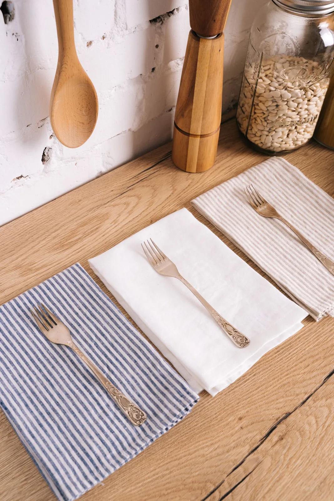 Striped kitchen towels on a pale worktop beside wooden utensils