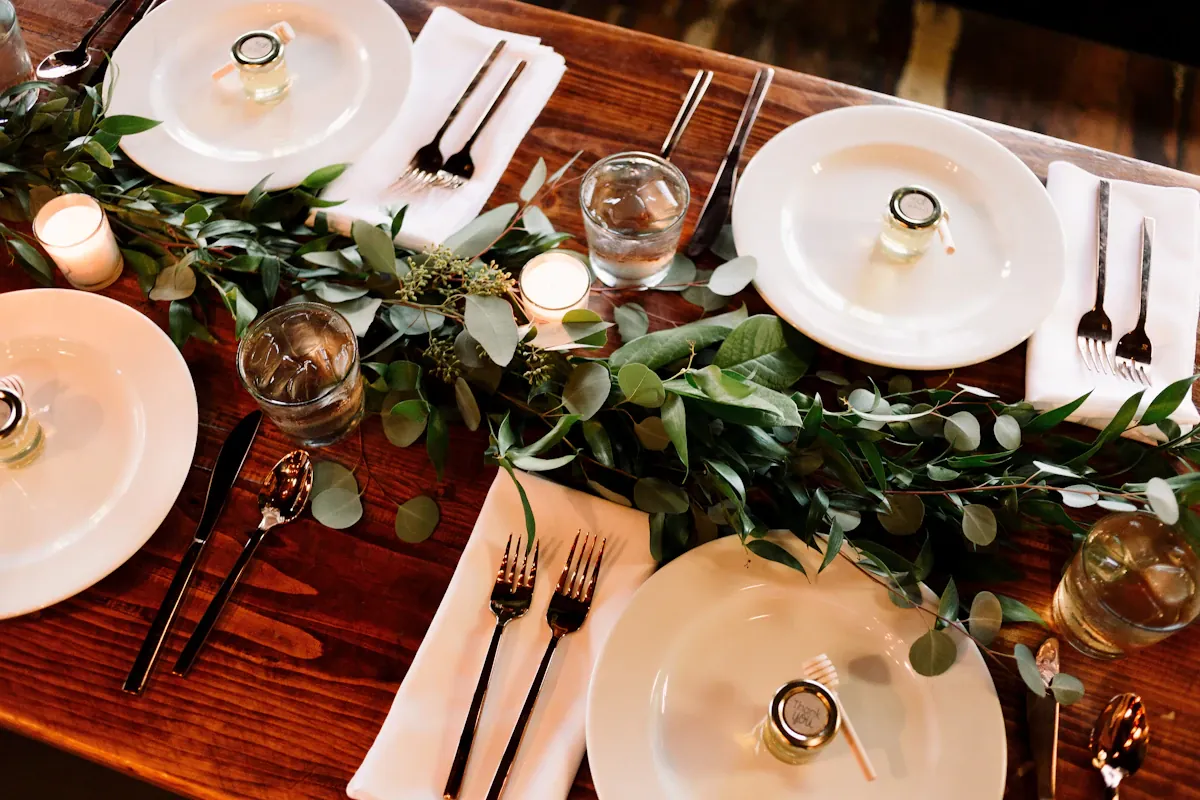 White lidded serving dishes, glasses and cutlery on a decorated table