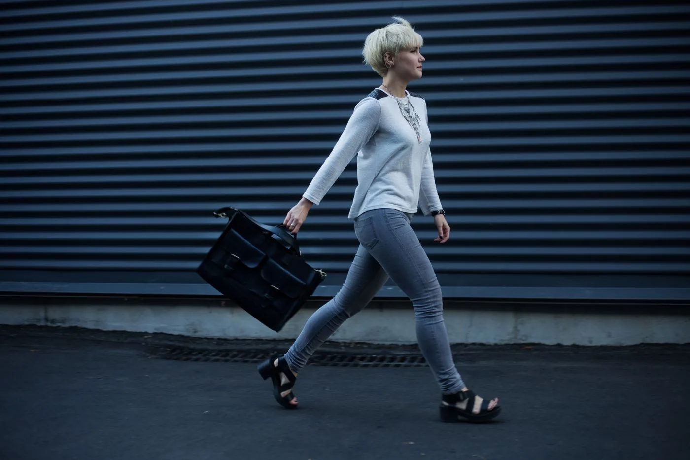 A woman in gray clothing carrying a large black handbag on a street