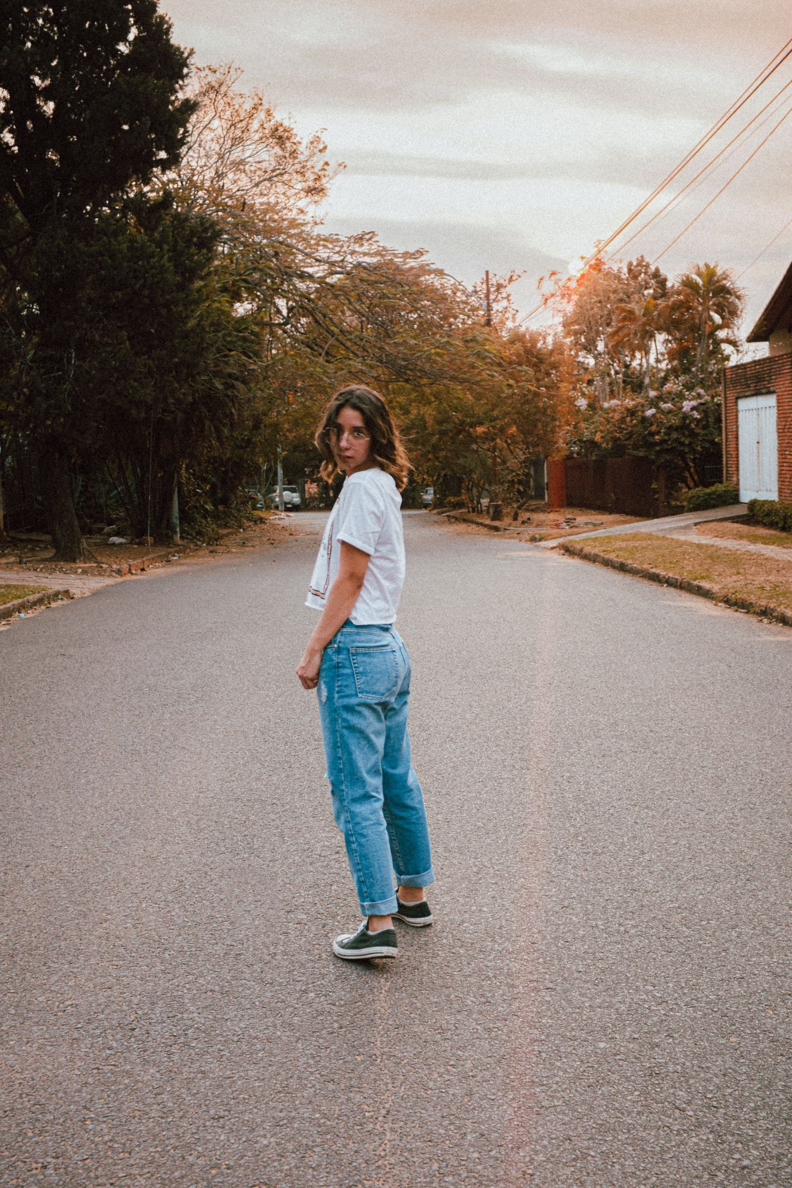 A woman wearing blue jeans and a pale top on a residential street
