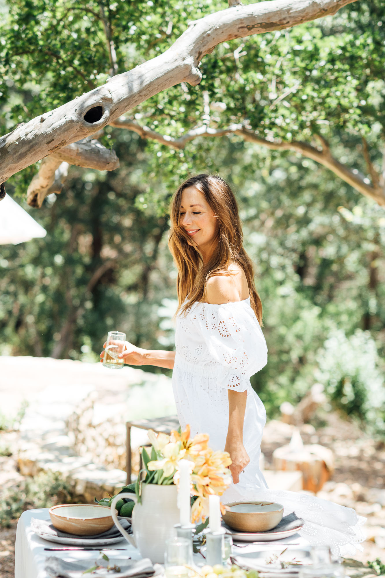 summer table setting ideas, Camille Styles summer dinner party table in backyard with trees, white dress