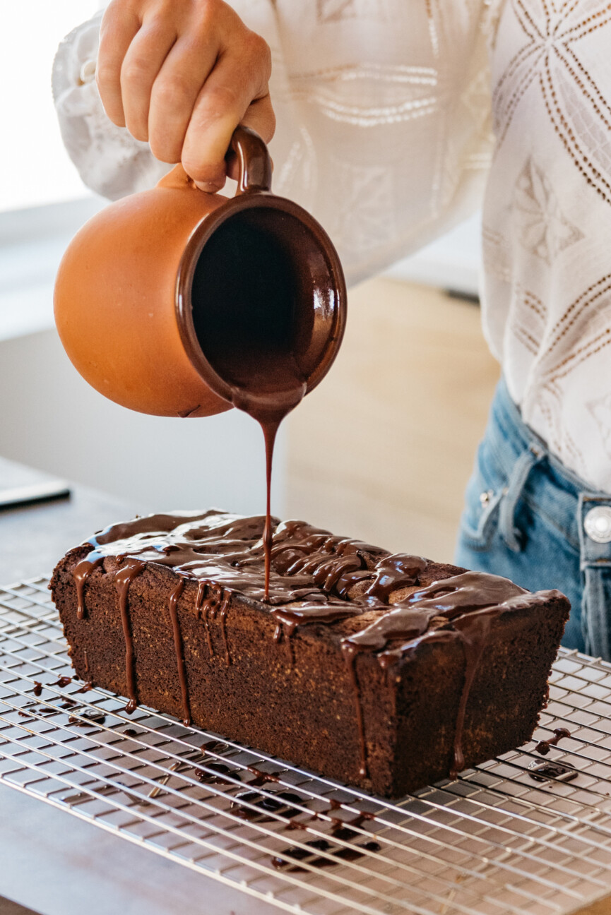 camille styles in kitchen pouring glaze over chocolate cake