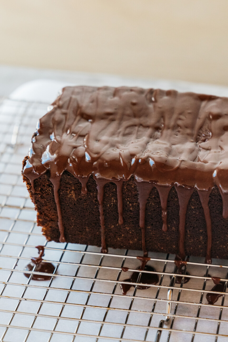 camille styles in kitchen pouring glaze over chocolate cake