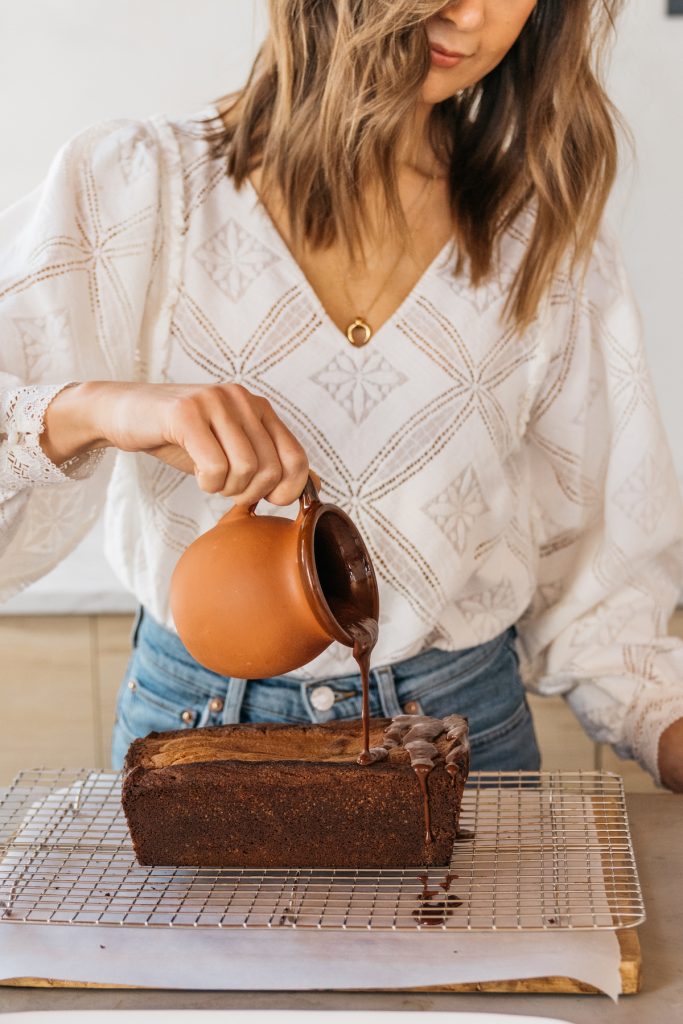 camille styles in kitchen pouring glaze over chocolate cake