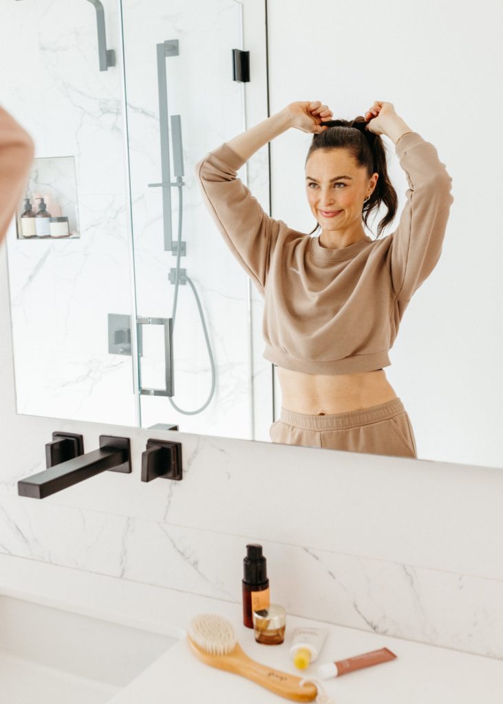 Megan Roup puts hair in a ponytail in her home bathroom_natural products for curly hair