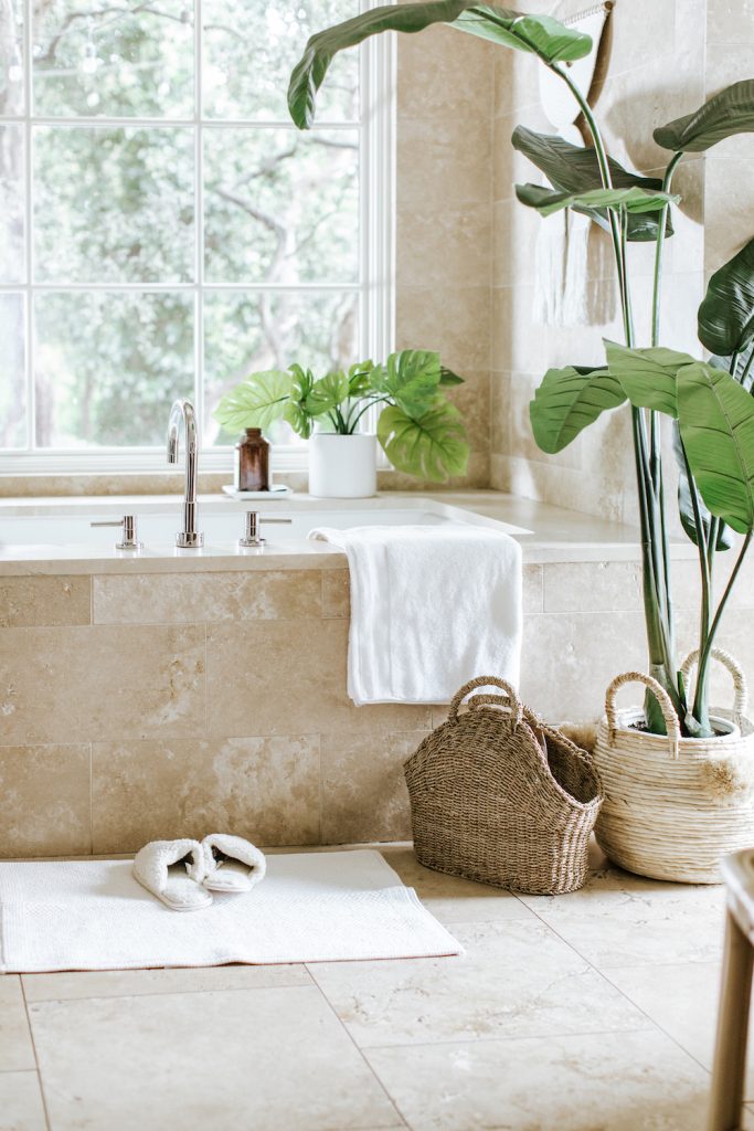 Camille Styles' bath tub, surrounded by bird of paradise plant and Monstera in white pots_hammam exfoliation