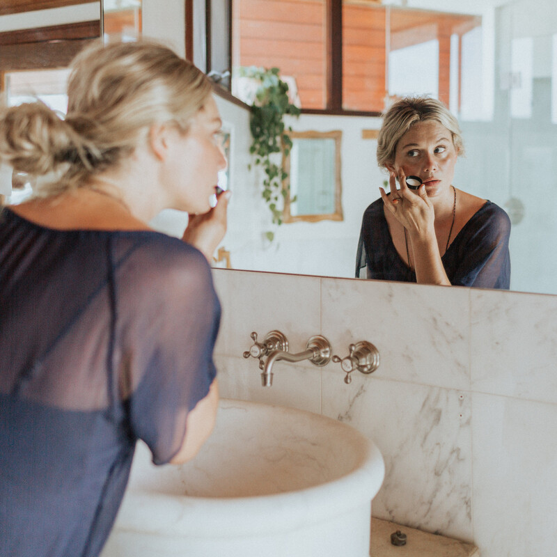 woman applying skincare treatment over bathroom sink
