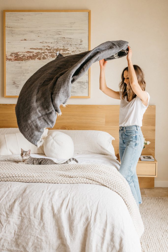 Camille Styles makes bed with cat Clementine sitting on mattress_how to wake up easier