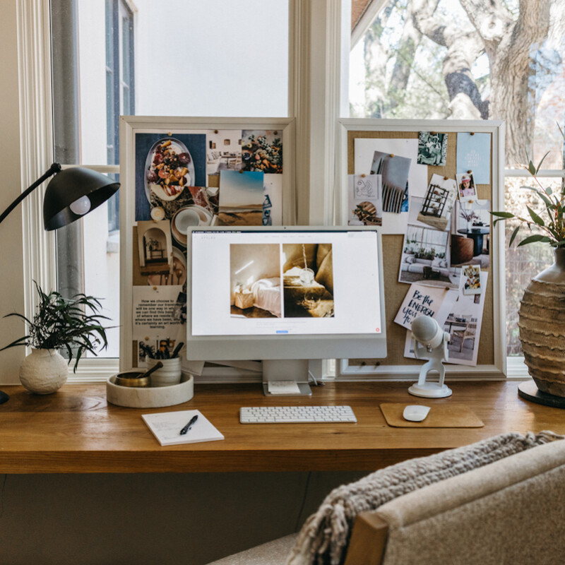 Modern desk with silver monitor in front of two vision boards.