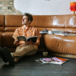 Man sitting on floor flipping through magazines.