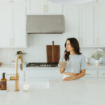 Woman drinking matcha at kitchen counter.