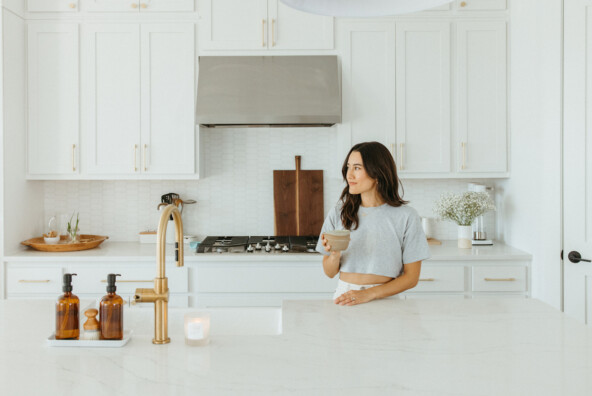 Woman drinking matcha at kitchen counter.