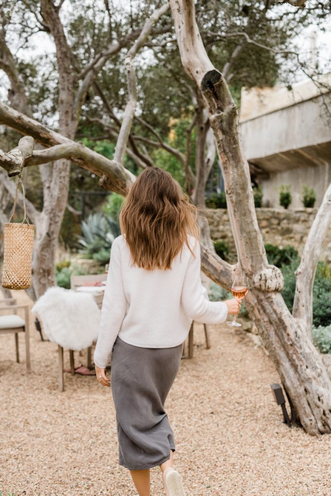 Camille Styles walking outside holding rosé_how to treat back acne