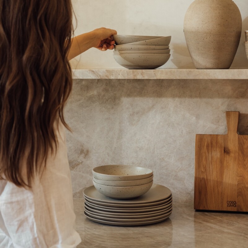 woman putting away ceramics on organized kitchen shelves
