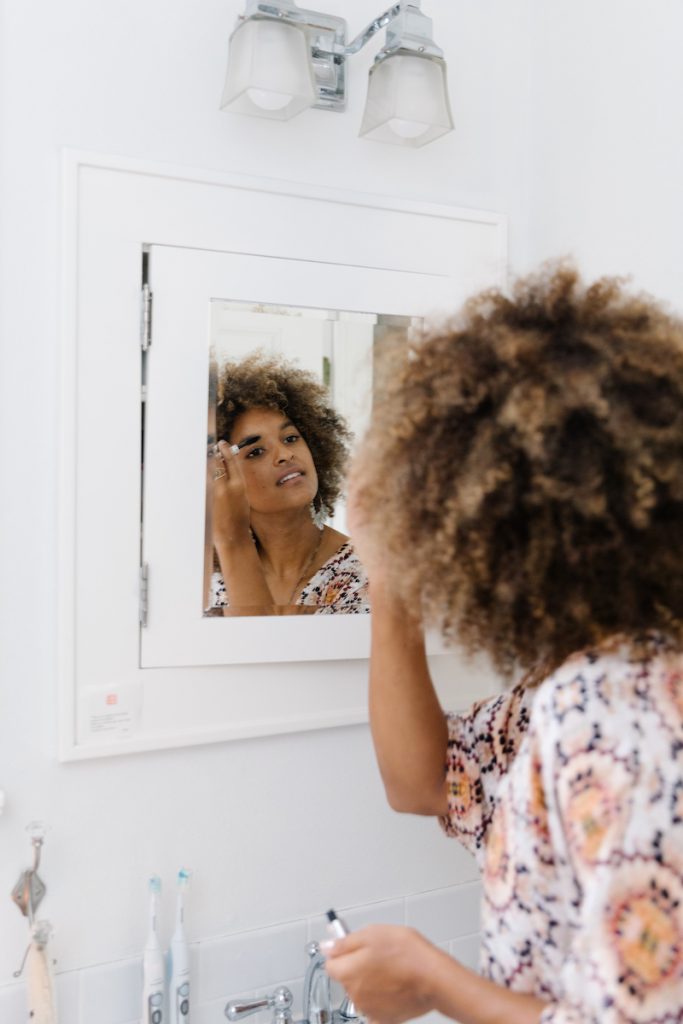 Riley Reed applying makeup in mirror_things to do on a rainy day
