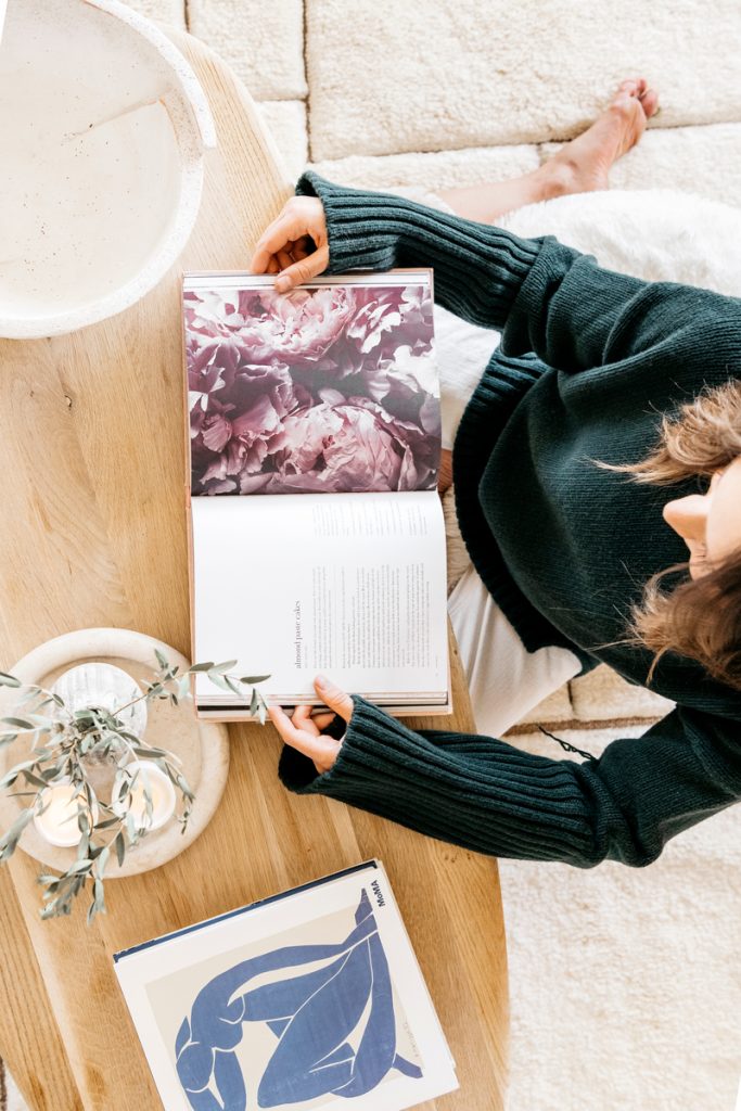 Camille Styles reading design books on coffee table_sober october