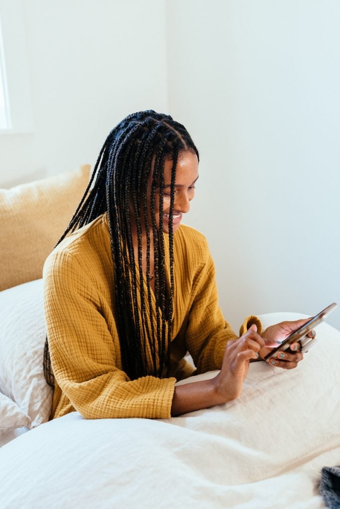 Shanika Hillocks using phone in bed_best story podcasts