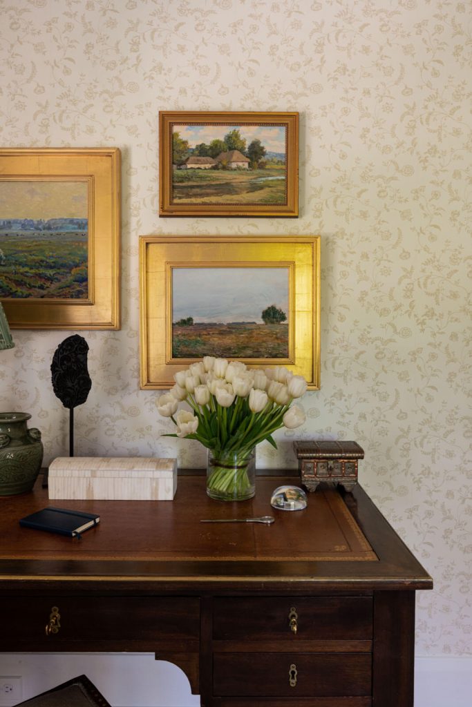 Vintage desk with antique art on walls.
