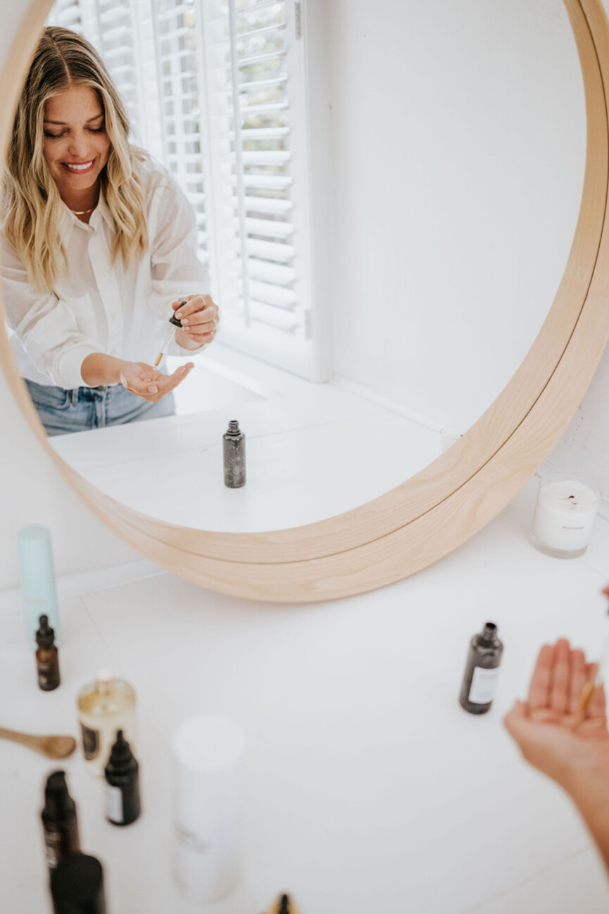 Woman applying hyaluronic acid in mirror.
