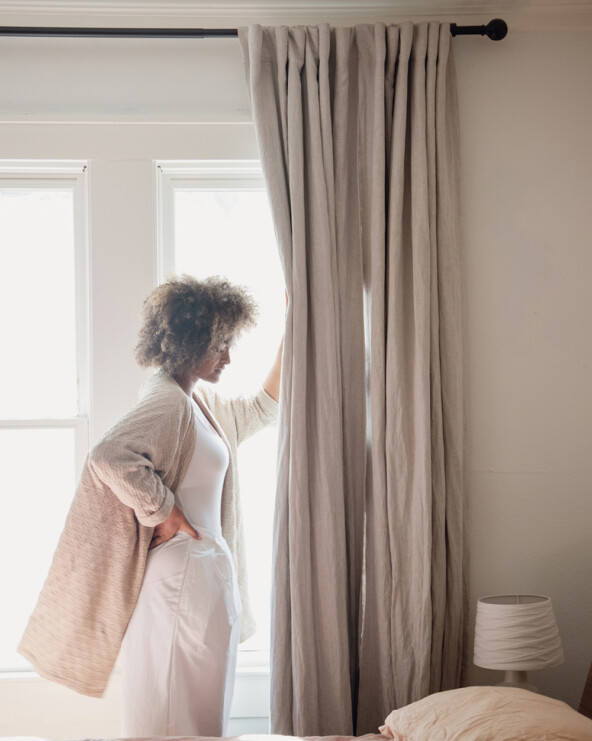Woman opening curtains.