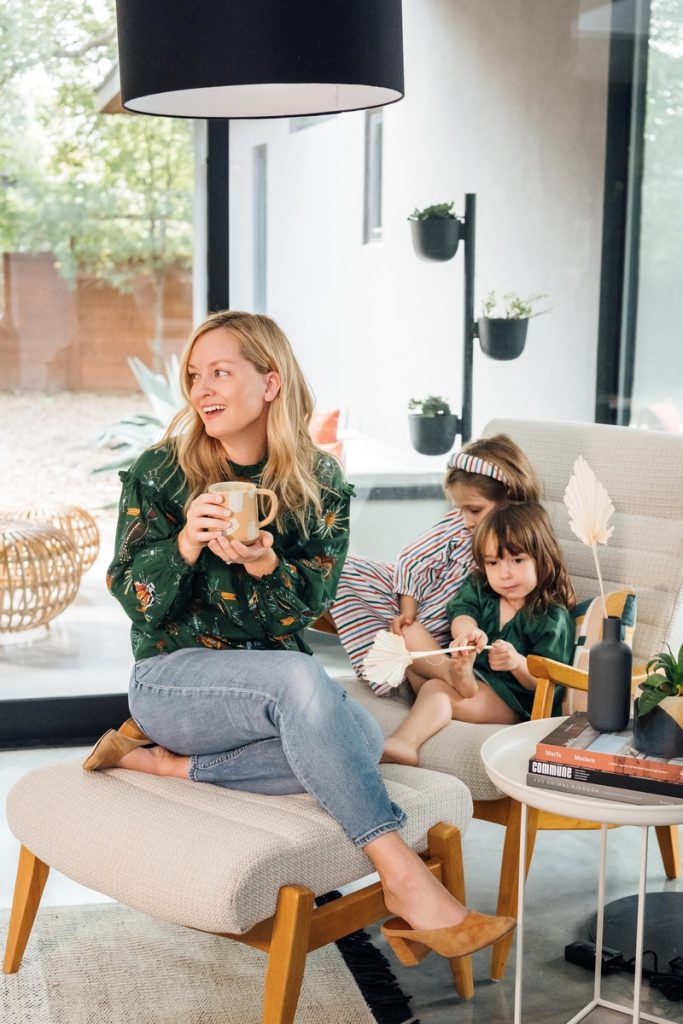 Woman with two small daughters sitting on chair.