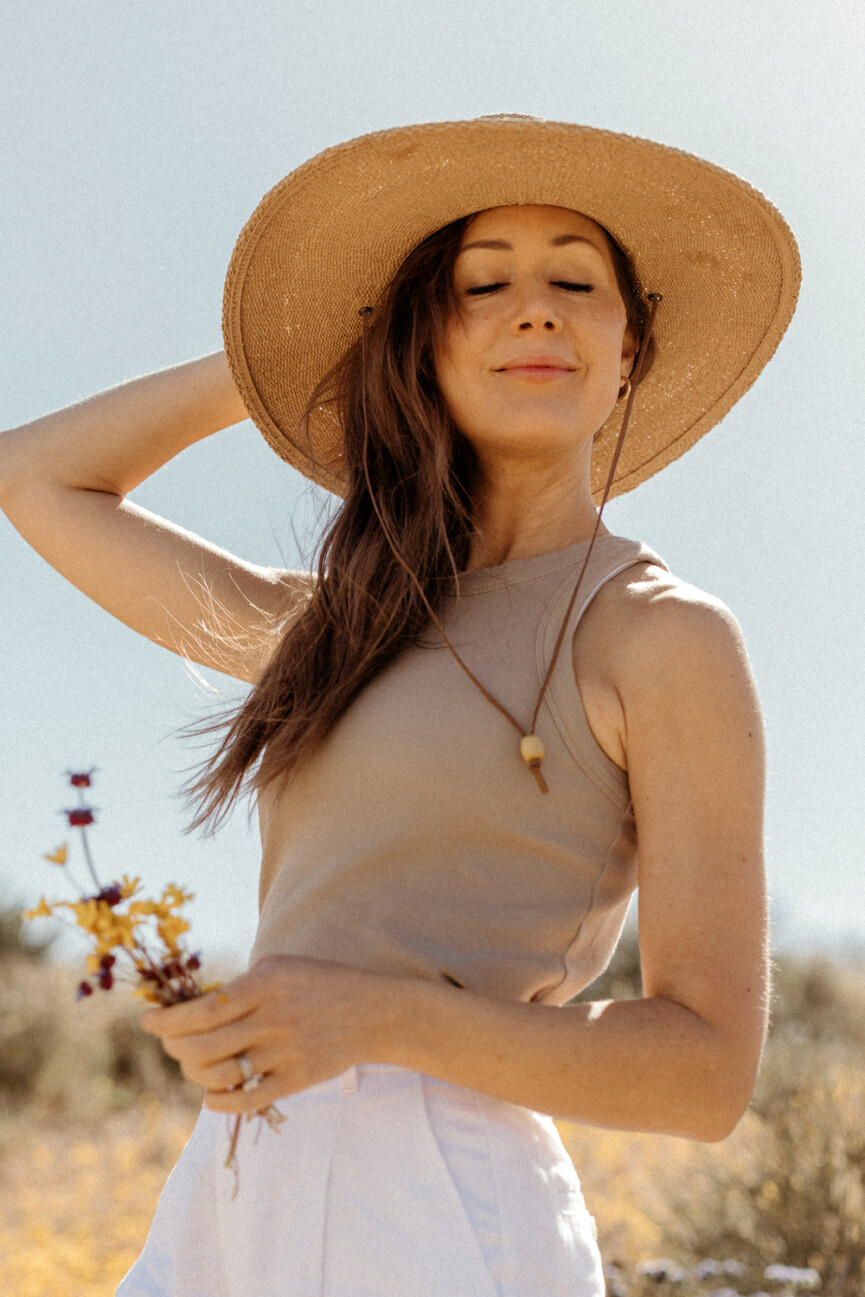 camille styles in joshua tree with wildflowers in straw hat