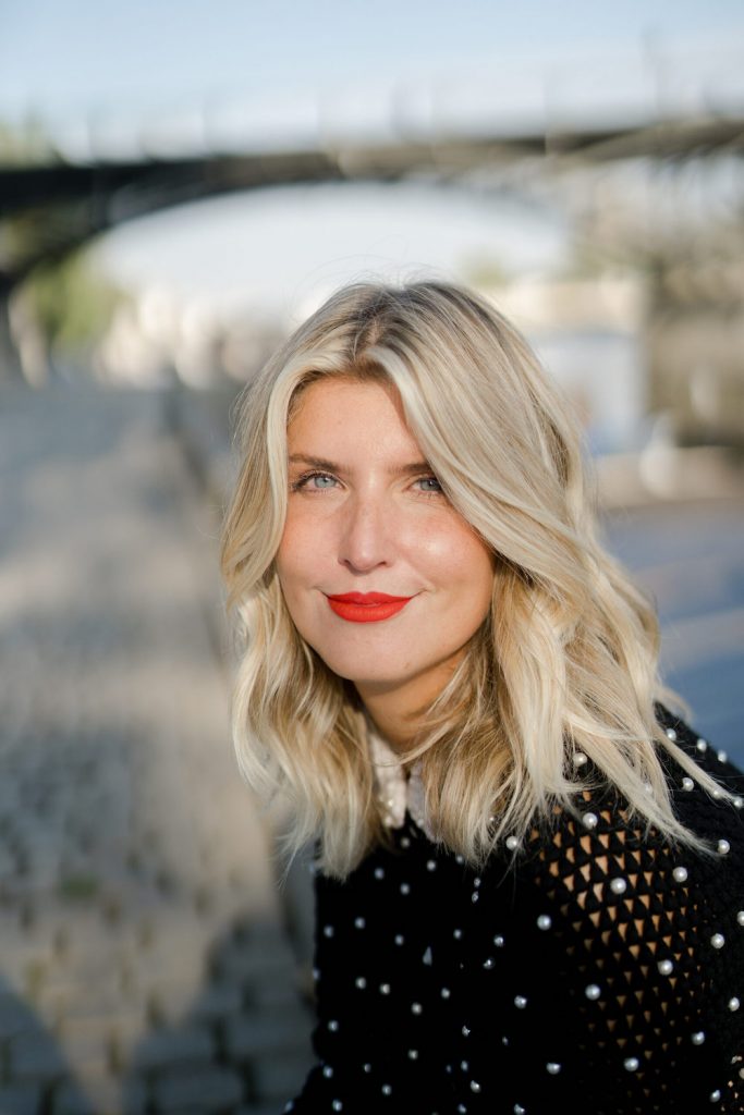 Headshot of Anna Kloots wearing red lipstick and black shirt.