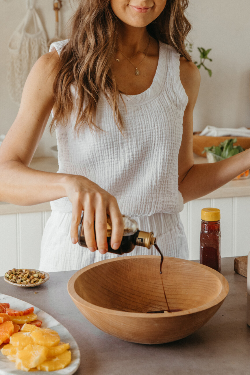 Camille Styles pouring balsamic vinegar into bowl_raddichio citrus prosciutto salad