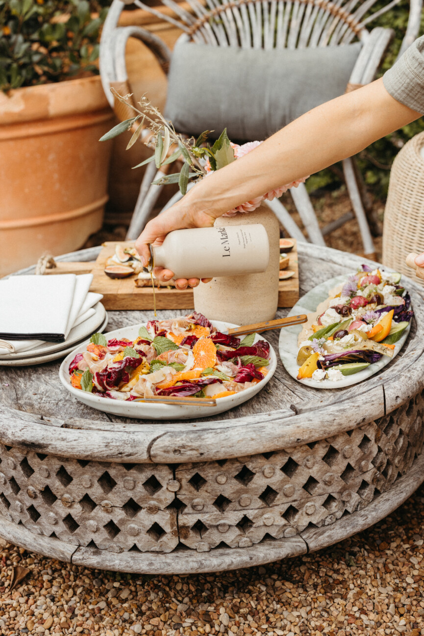 pouring balsamic vinegar on raddichio citrus prosciutto salad