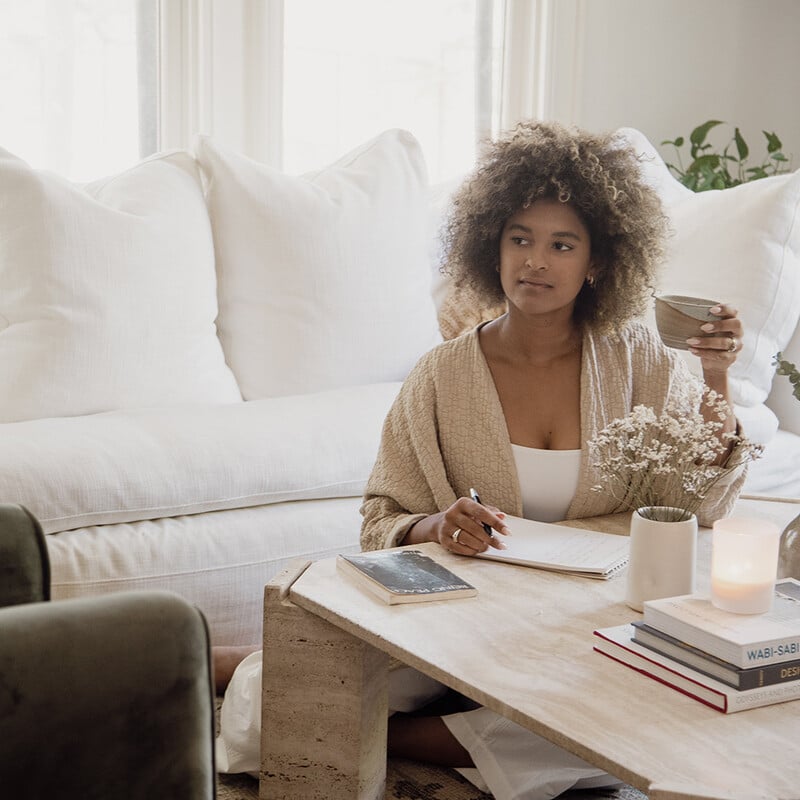 Woman journaling in living room.