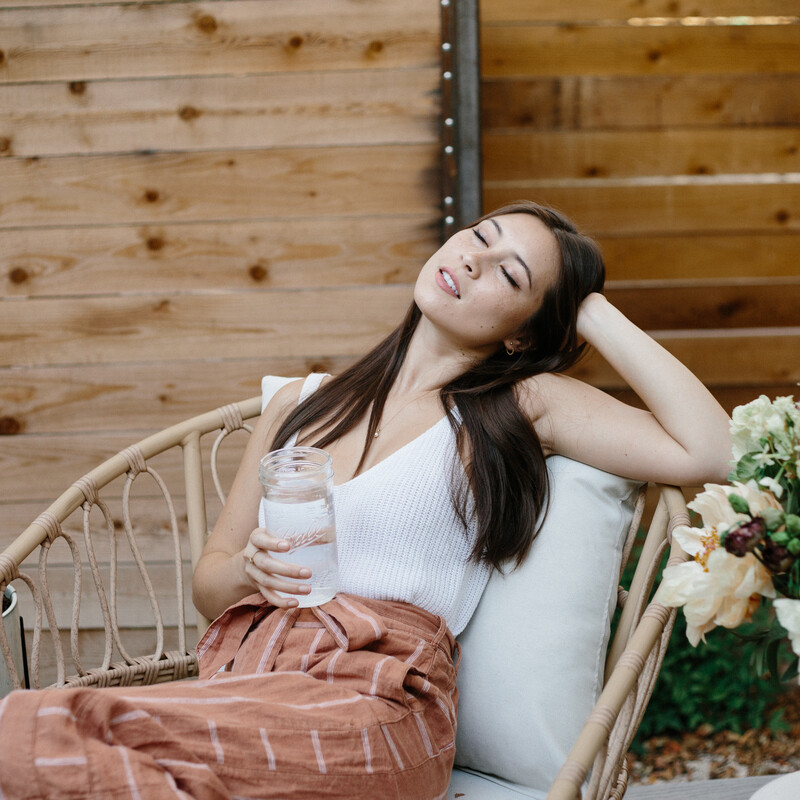 Woman drinking water on patio outside.