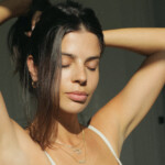 Woman tying up hair in ponytail.