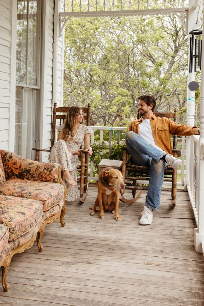 Man and woman sitting on porch with dog.
