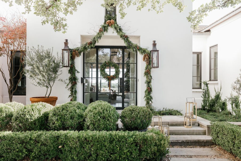 Camille Styles Holiday Decor 2023-Christmas front porch decor with evergreen garland and casa zuma holiday wreath and candles
