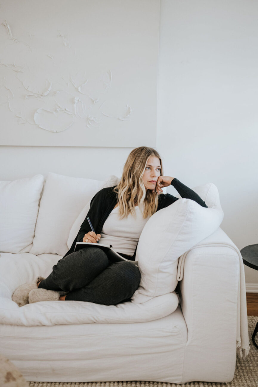 Woman journaling on couch.