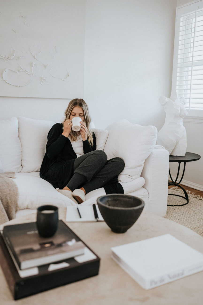 Woman drinking tea on couch.