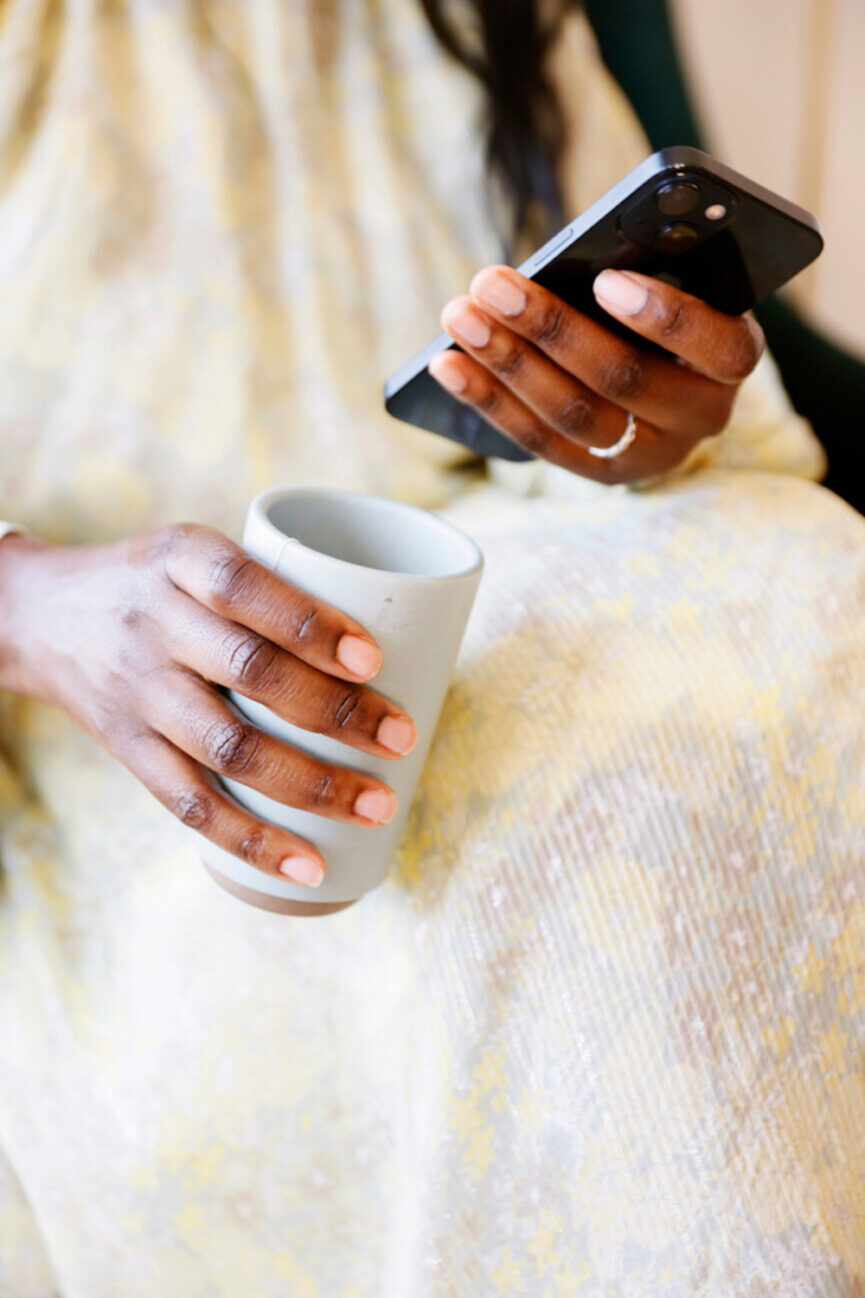 Holding cellphone and mug.