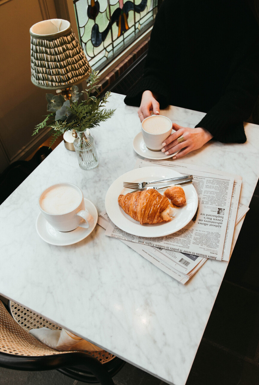 Drinking coffee and eating croissant.