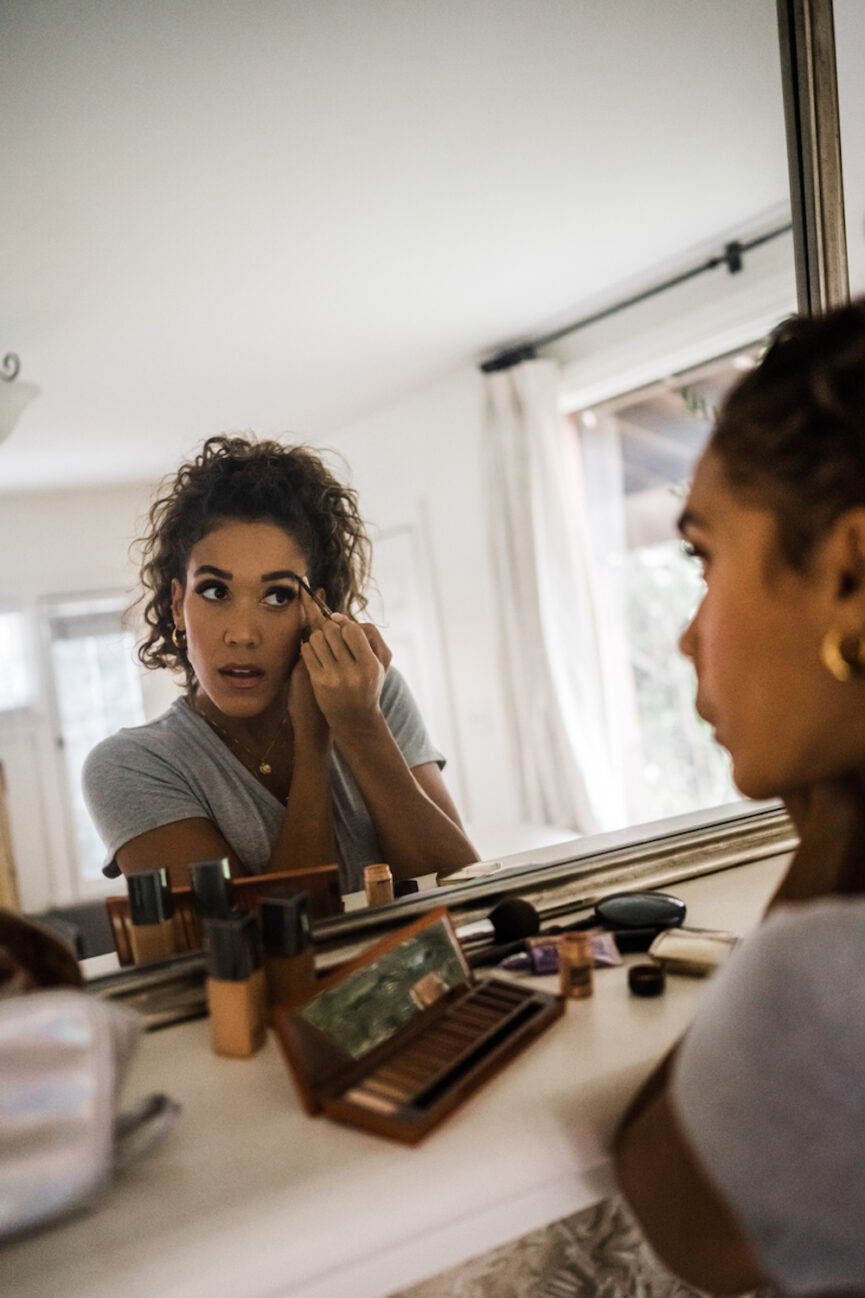 Woman applying makeup in mirror.