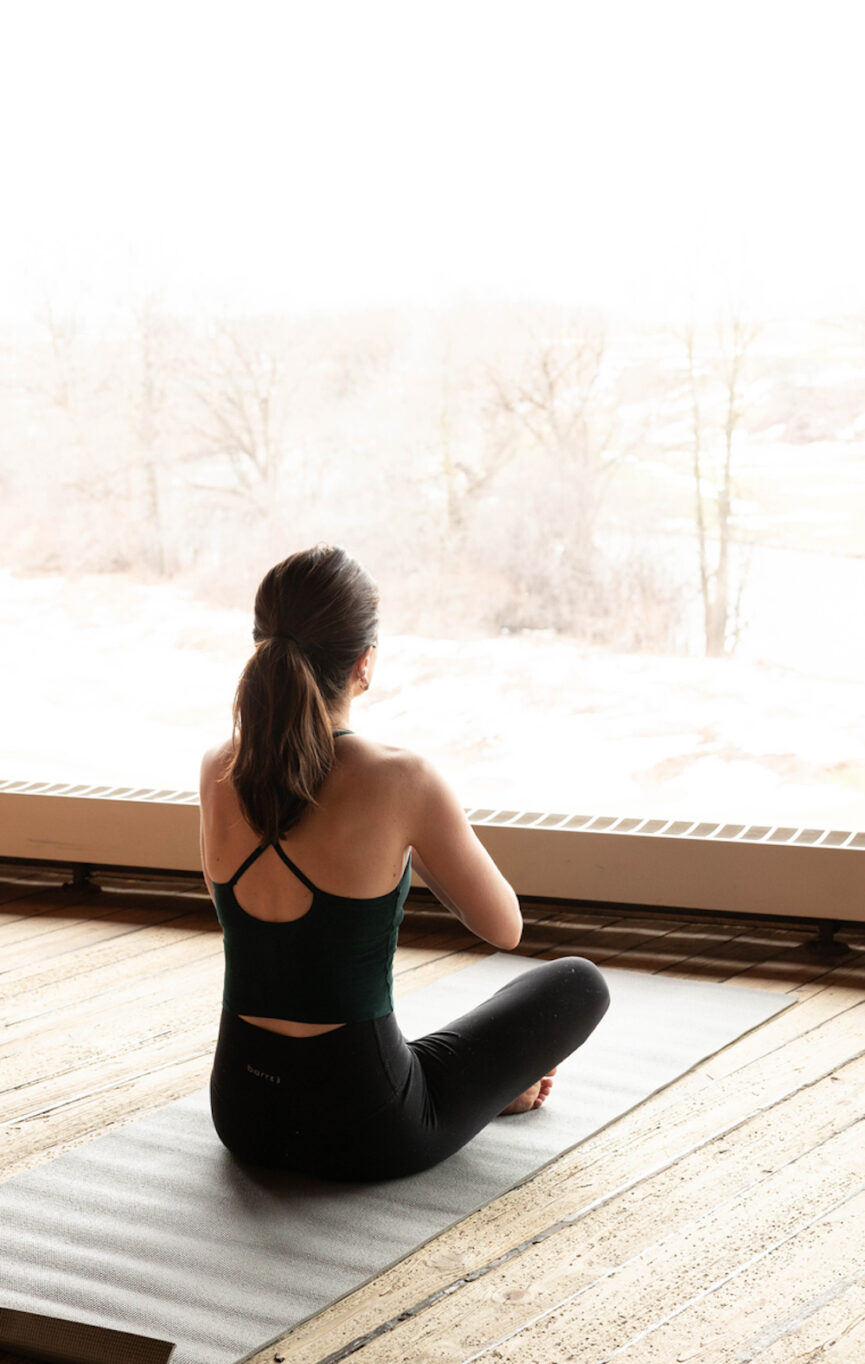 Woman sitting on yoga mat with hands to heart.