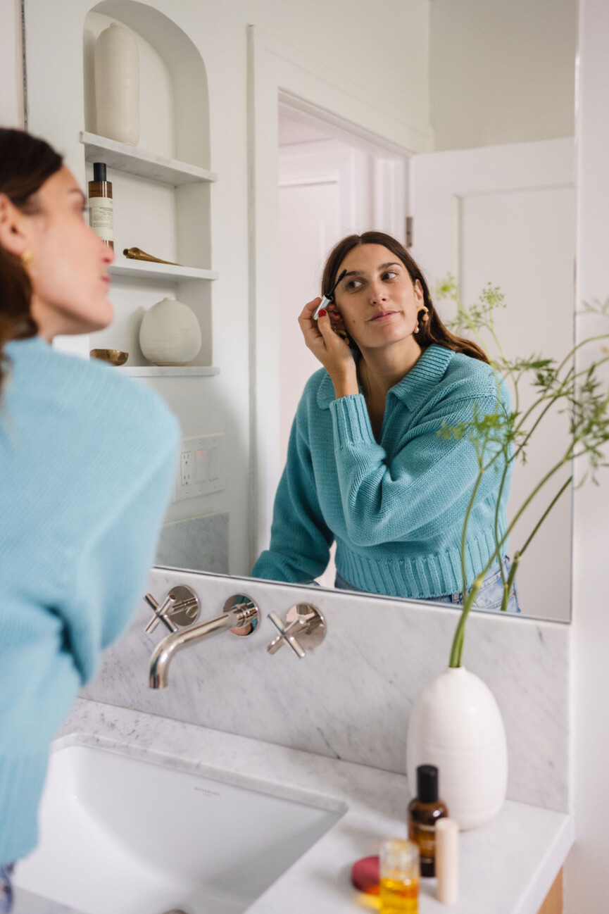 Woman applying makeup in mirror