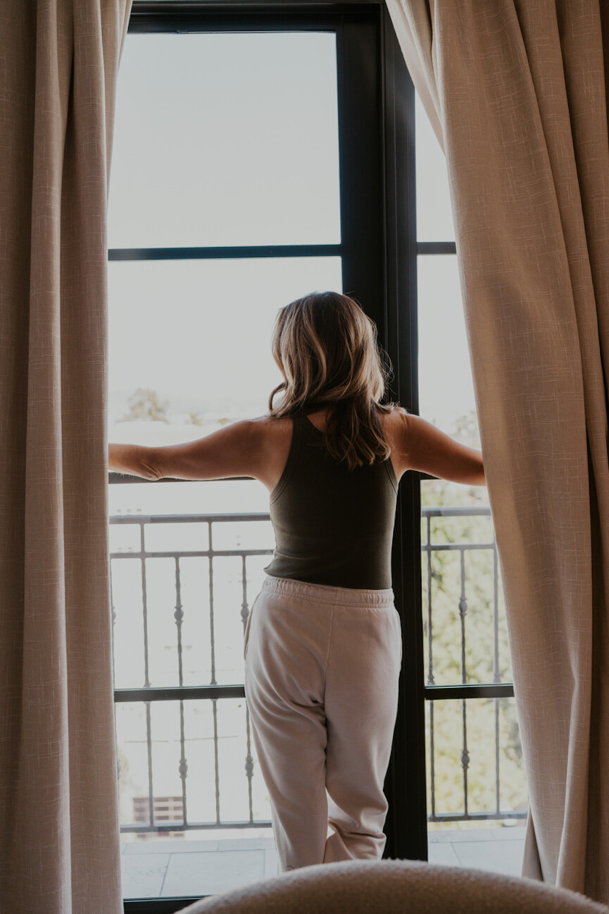 Woman opening window curtains.