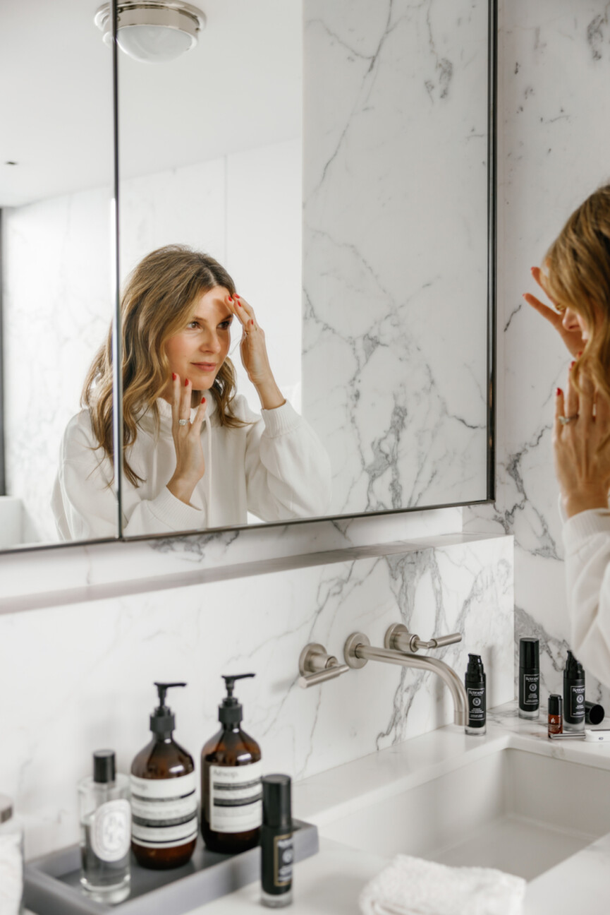 Woman washing face in the mirror.