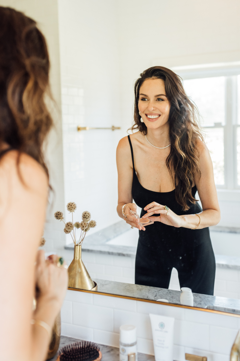 Woman with long brown hair at the mirror in the bathroom
