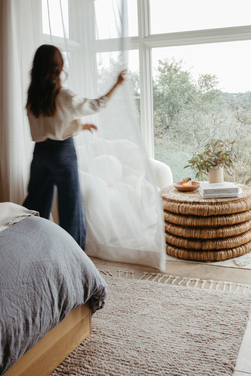 Woman pulling back curtains.