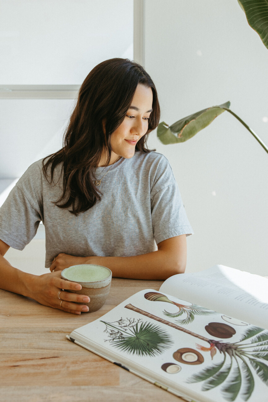 Woman reading book drinking matcha.