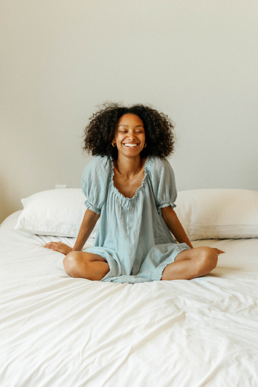 Woman sitting on bed in nightgown.