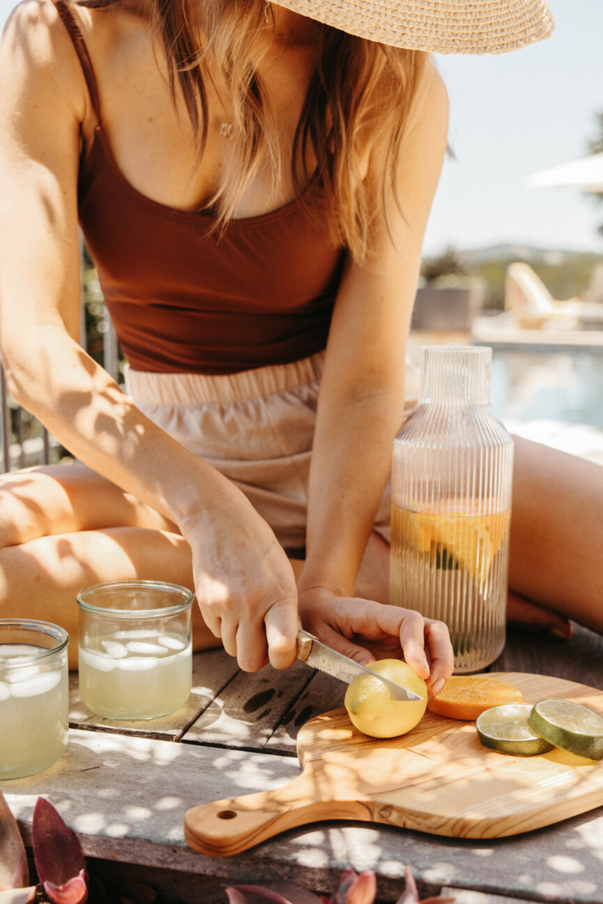 Woman wearing bathing suit cutting citrus.