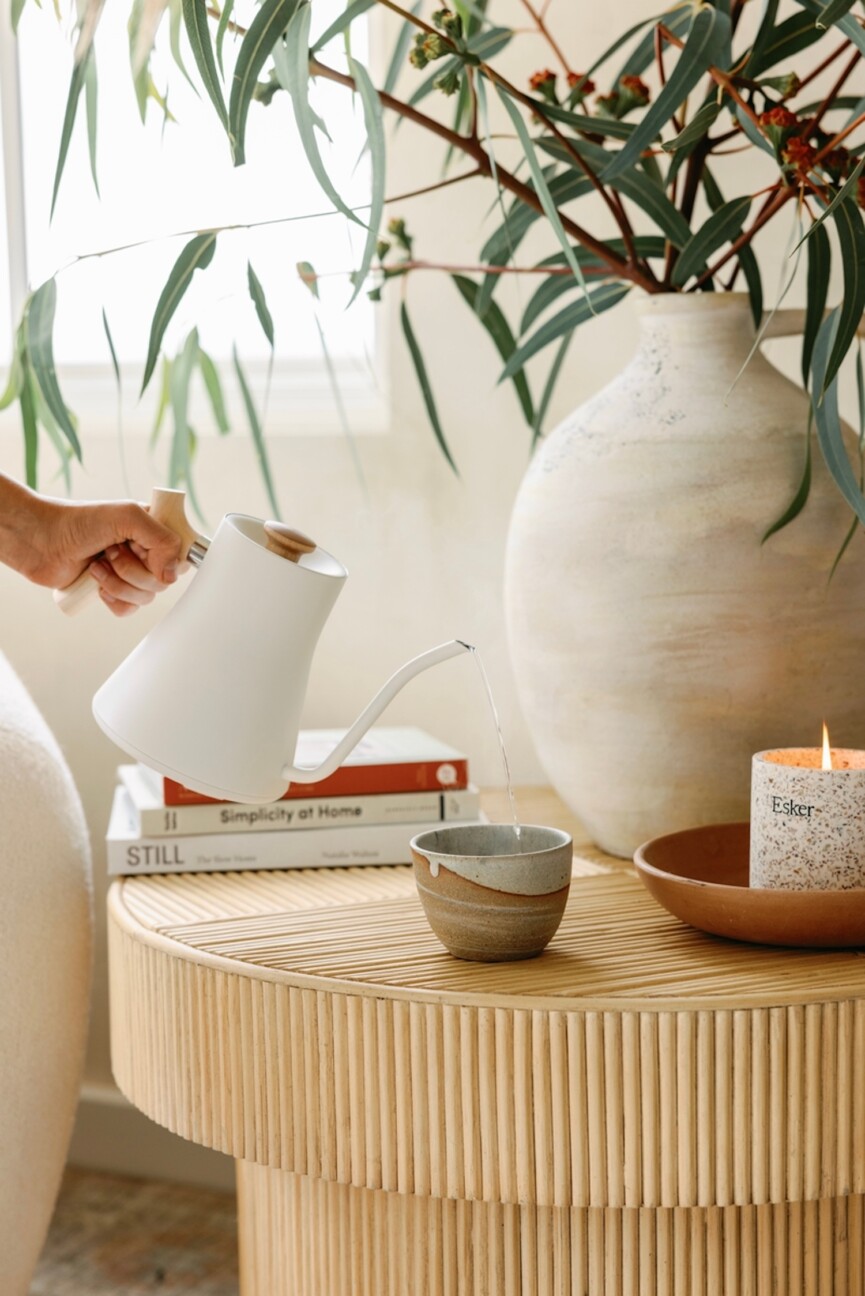 Woman pouring tea in electric kettle.